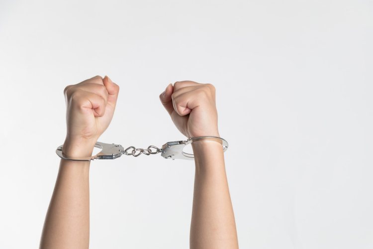 Raised arms with handcuffed wrists and clenched fists