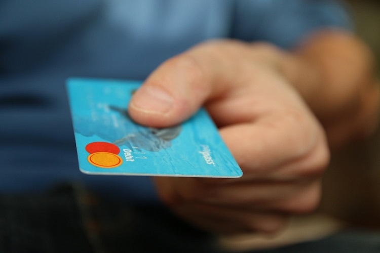 Blue credit card in hand of man with blue t-shirt