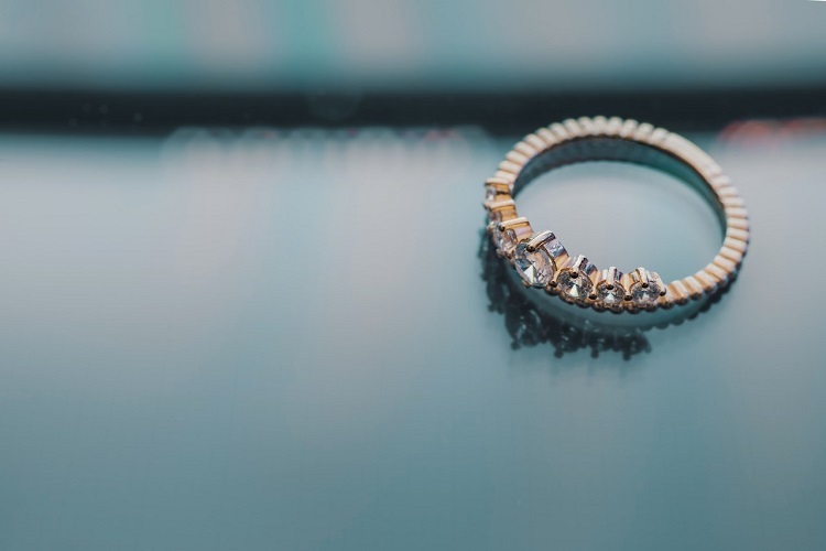 Diagmond engagement ring with gold band on translucent blue surface