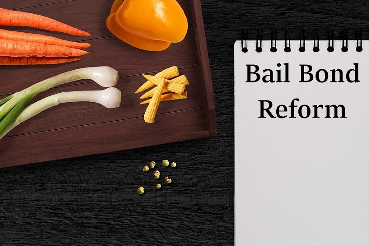 Notepad page labelled "Bail Bond Reform" beside cutting board with sliced vegetables