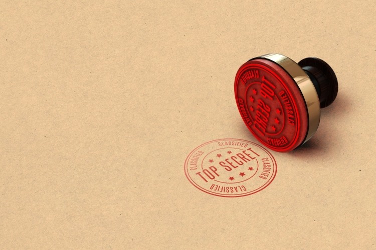 Red 'top secret' stamped onto light brown form beside adjacent stamper
