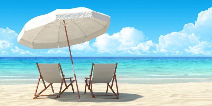 Two beach chairs under large umbrella overlooking scenic ocean