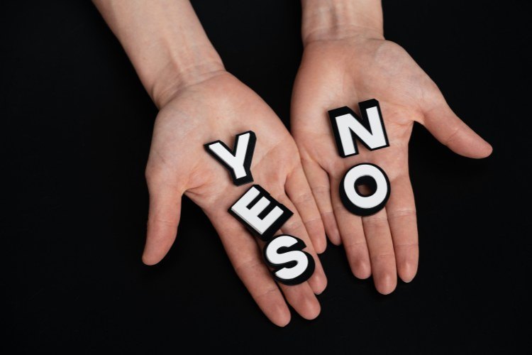 Two outstretched hands holding white letter cutouts spelling words 'yes' and 'no'