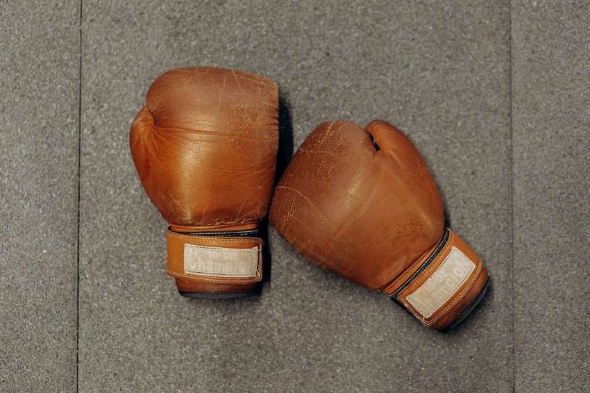 Brown, leather boxing gloves positioned on hard surface in fighting position