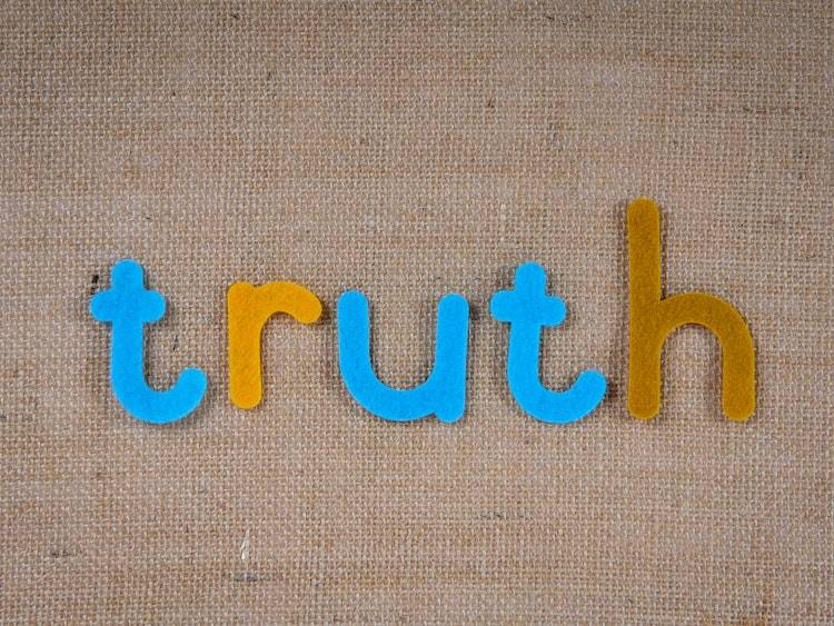 Yellow and blue magnet letters spelling 'truth' on flat layer of burlap cloth