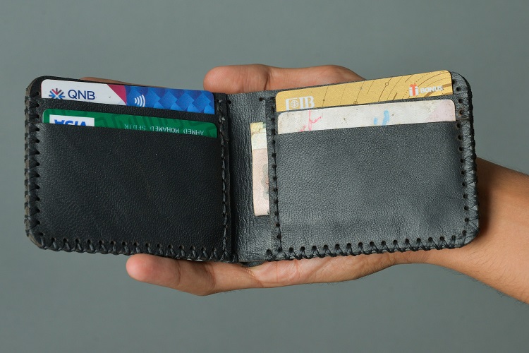 Black leather wallet with several credit cards in pockets in outstretched hand